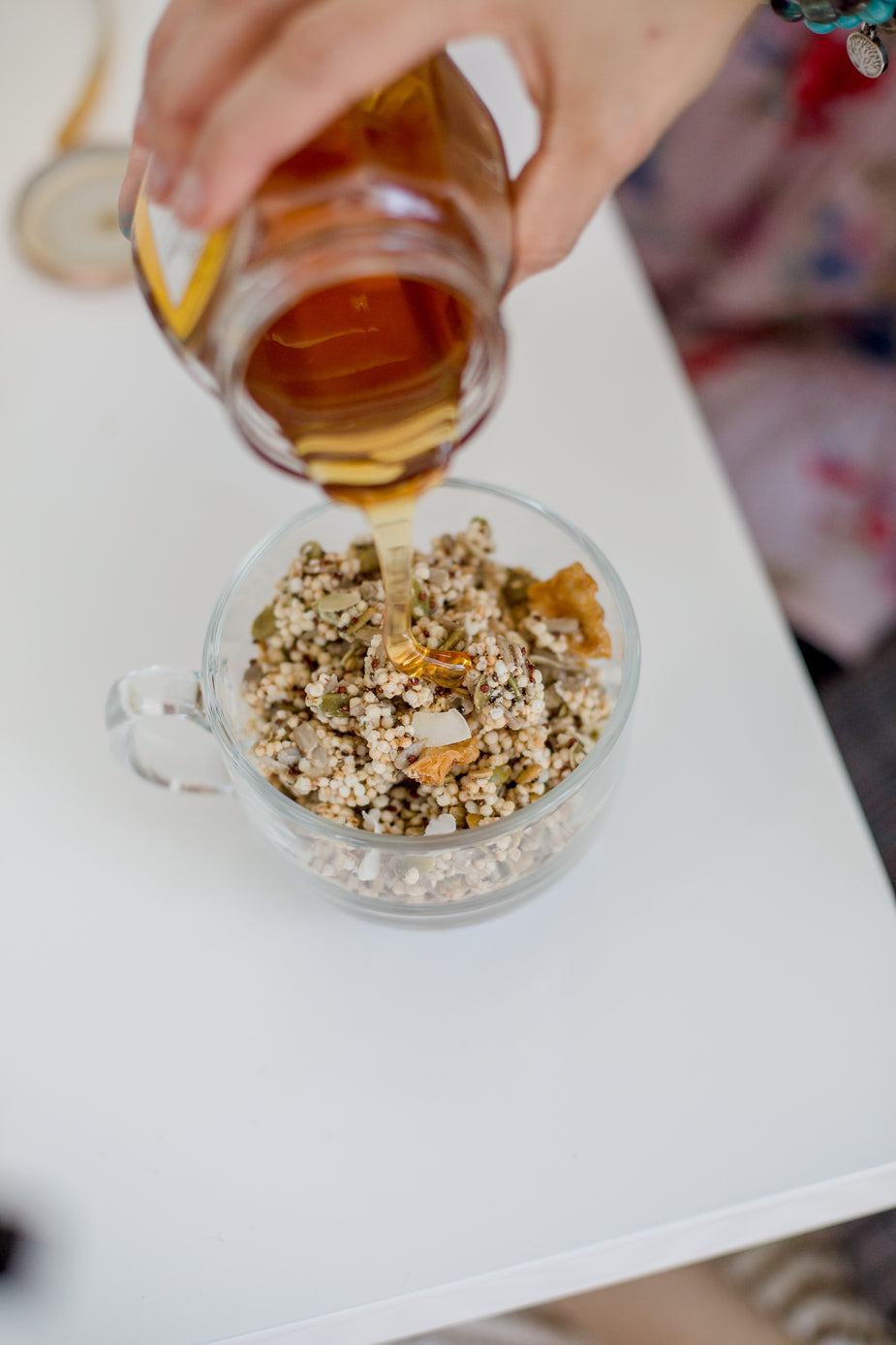 Rock sugar syrup being poured from glass measuring cup over granola parfait with yogurt and fresh berries