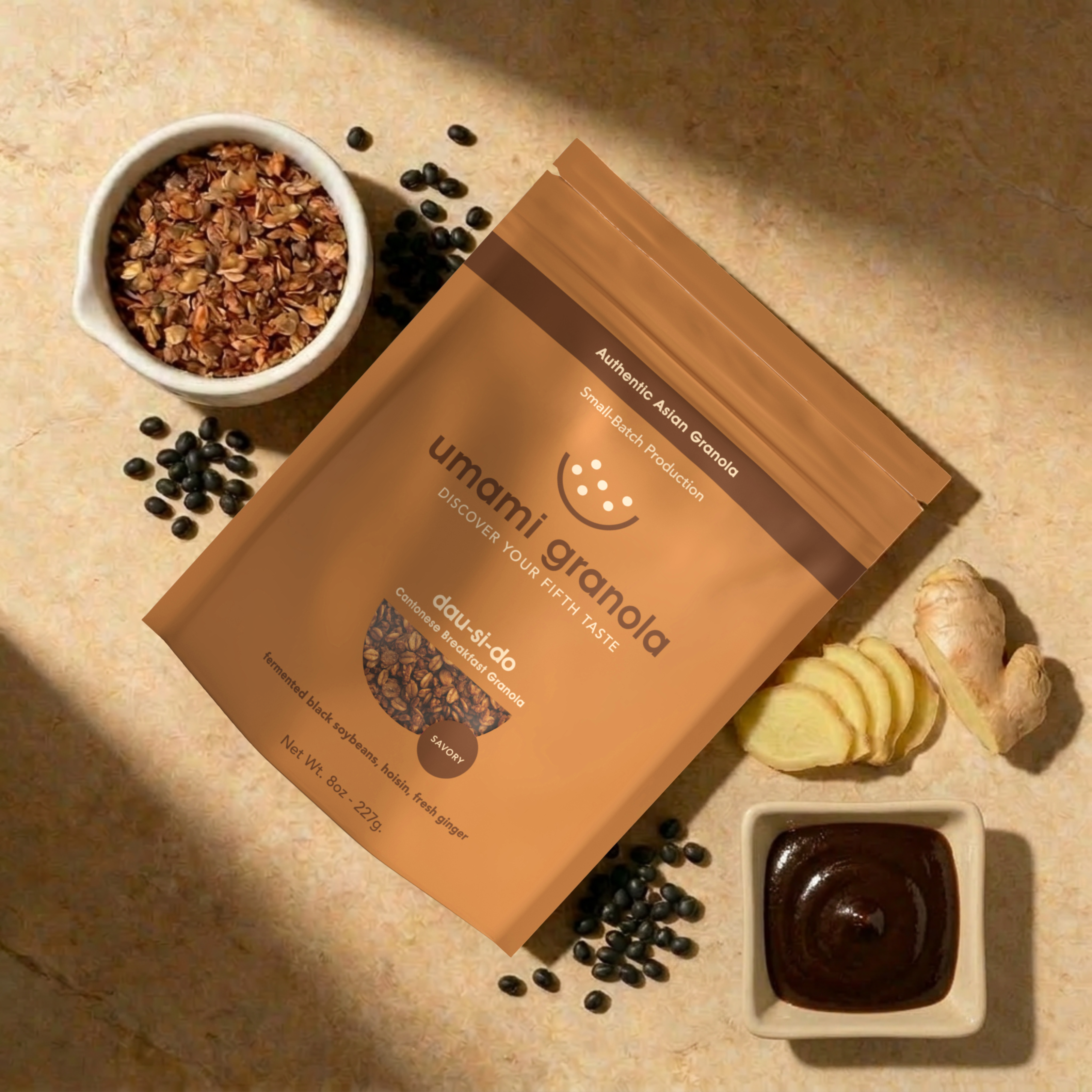Umami Granola packaging with granola, black beans, and a small dish of chocolate on a beige surface.
