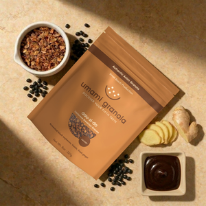 Umami Granola packaging with granola, black beans, and a small dish of chocolate on a beige surface.