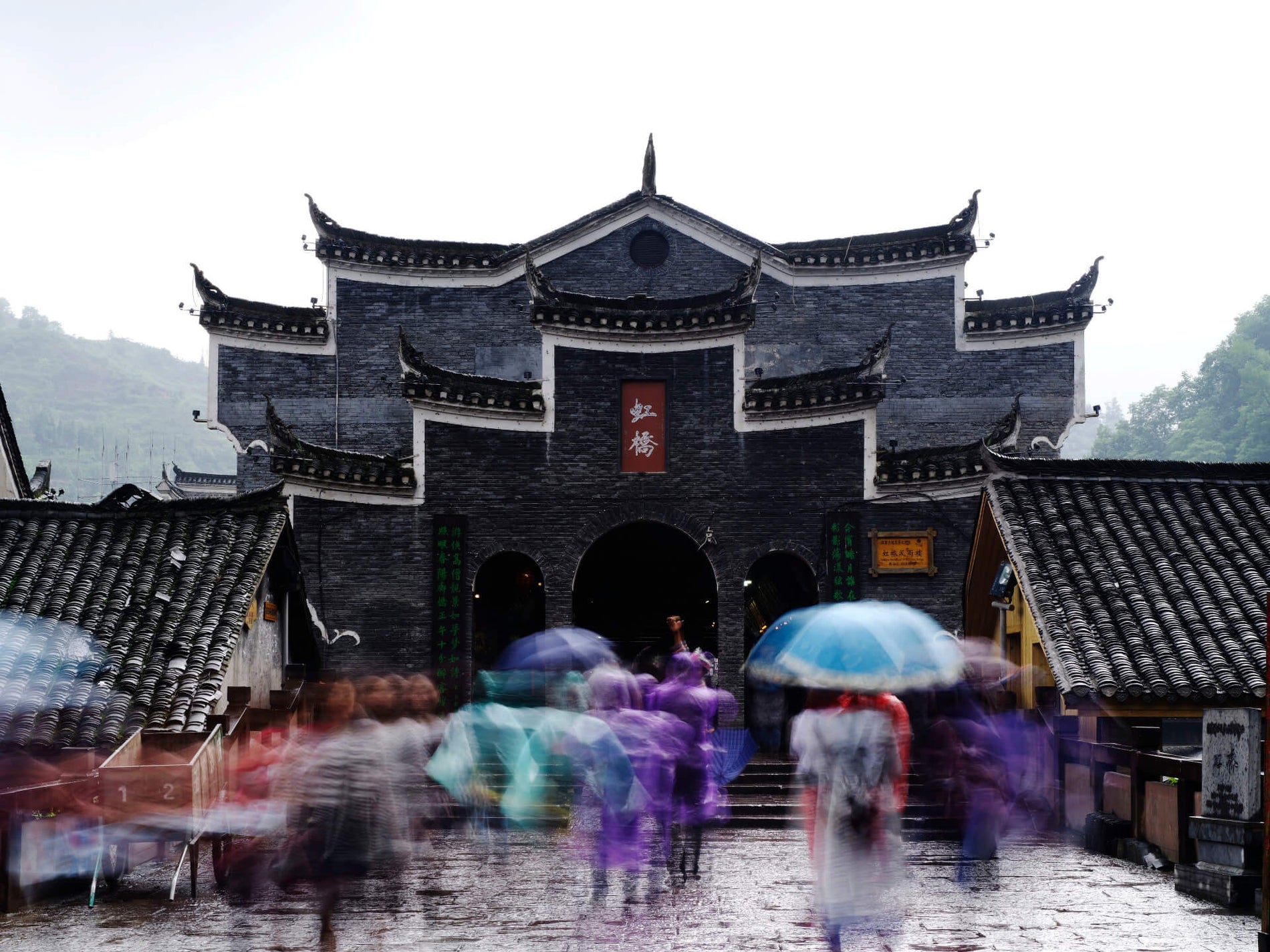Traditional Chinese architectural entrance with red lanterns and visitors in courtyard