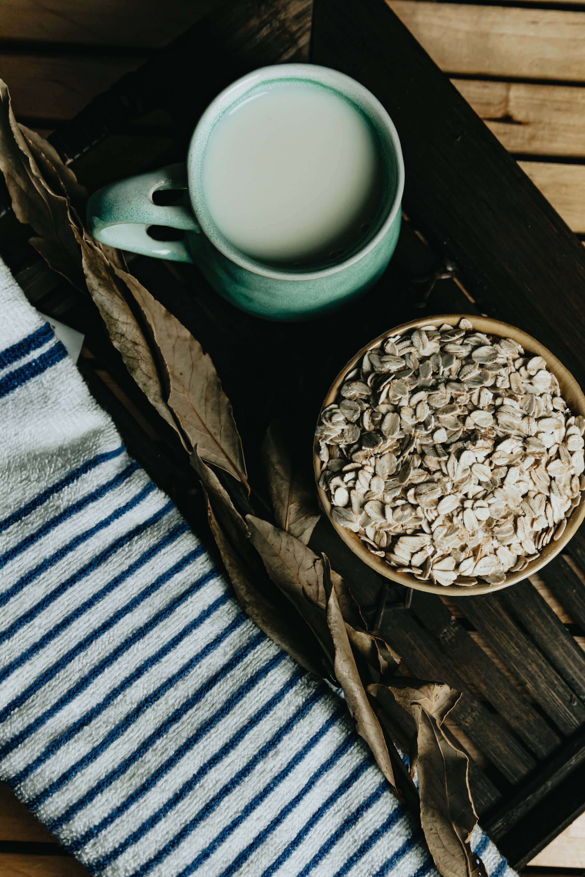 Tea cup and bowl of seeds on a wooden surface with striped fabric