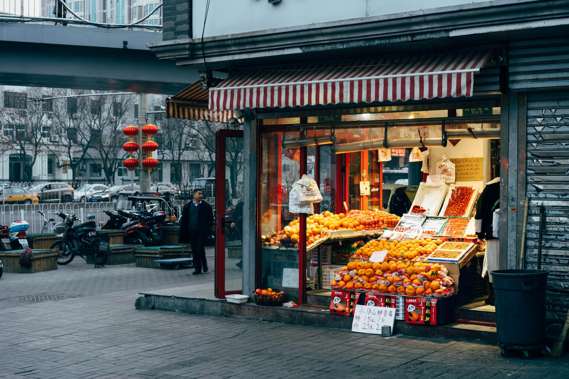 Traditional Asian market with produce displays and shoppers under covered walkway