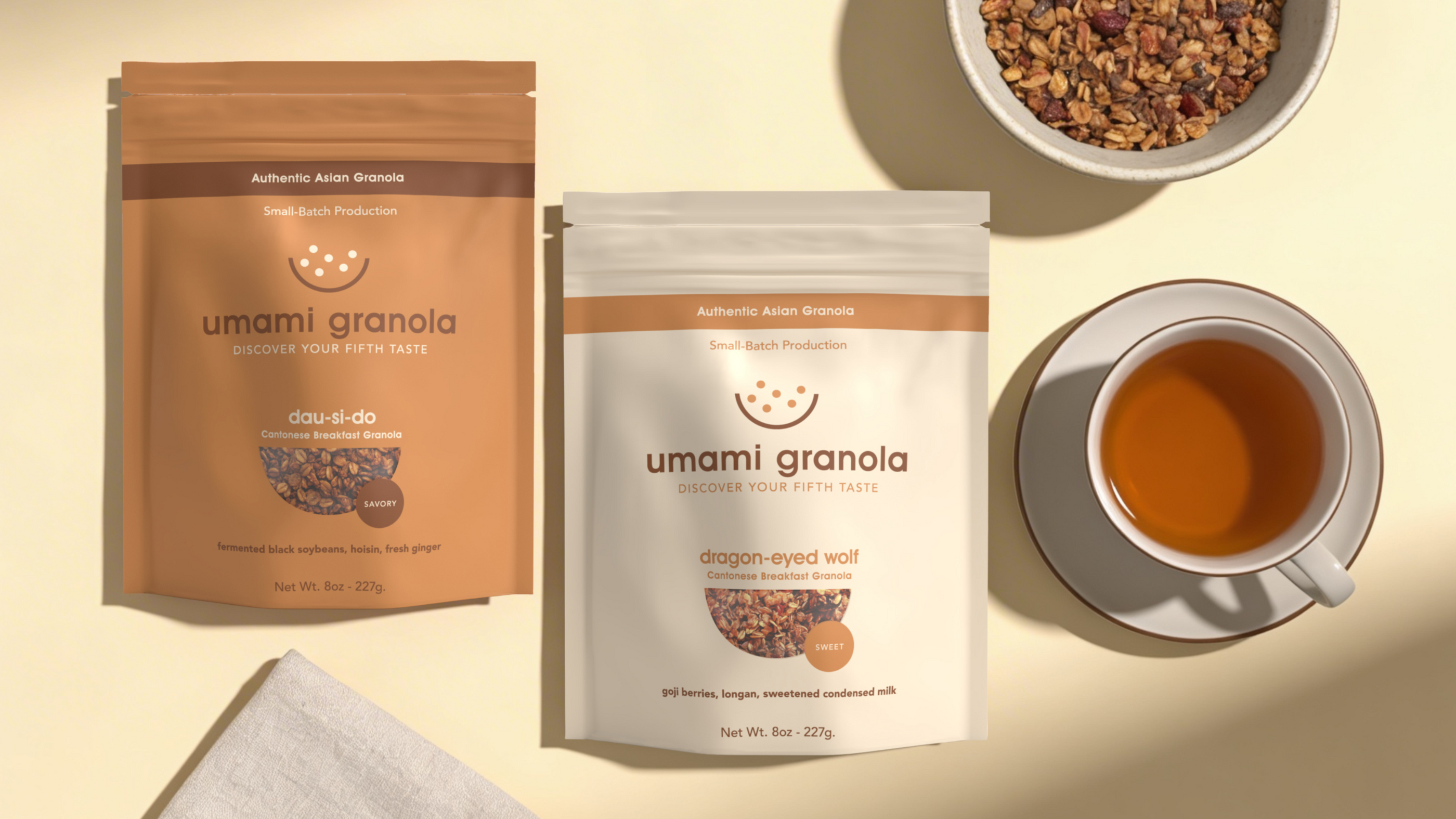 Umami Granola packages with a bowl of granola, a cup of tea, and a napkin on a beige background.